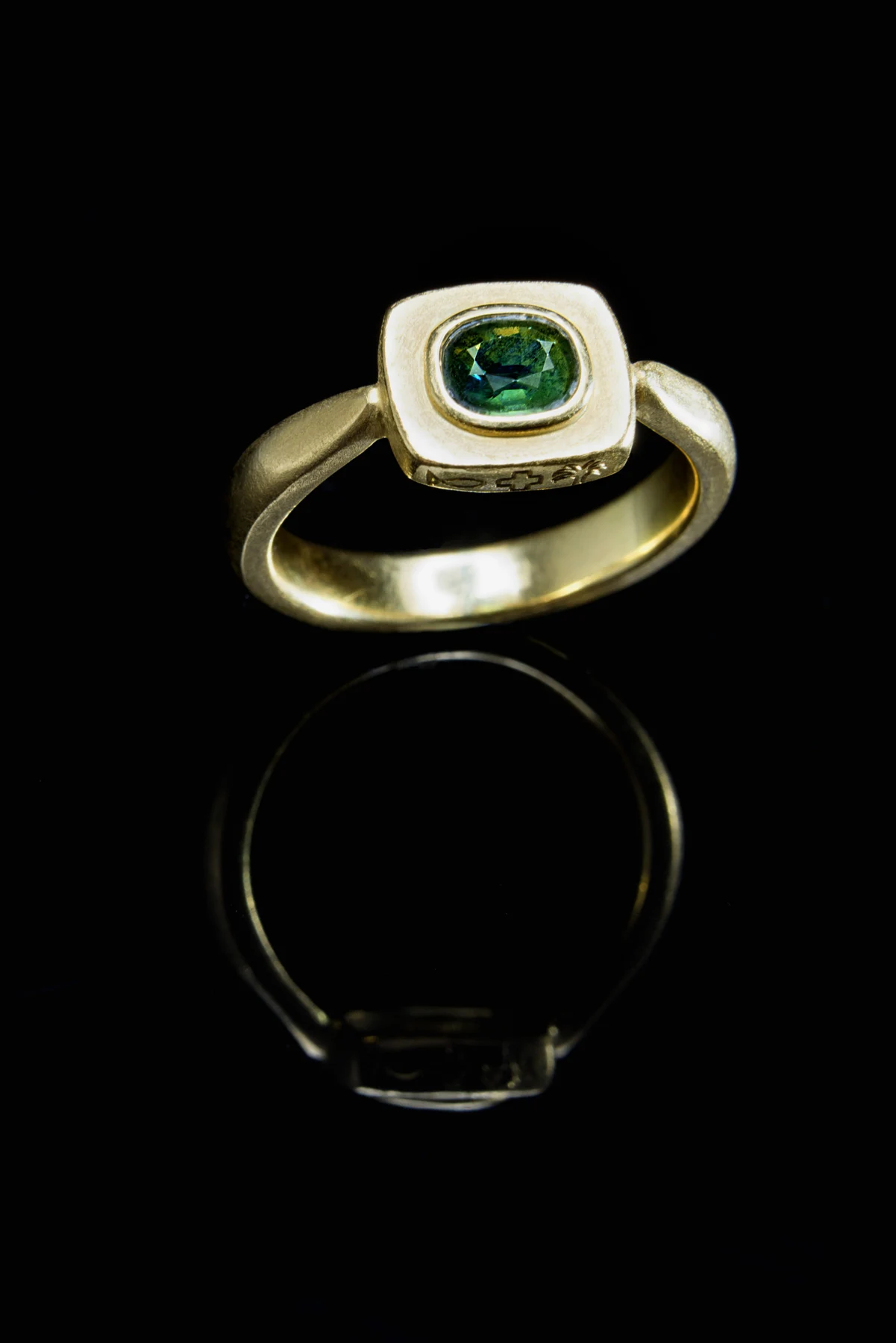 Bague à pierre verte entourée d’une monture dorée, création de la maison Spinelle
